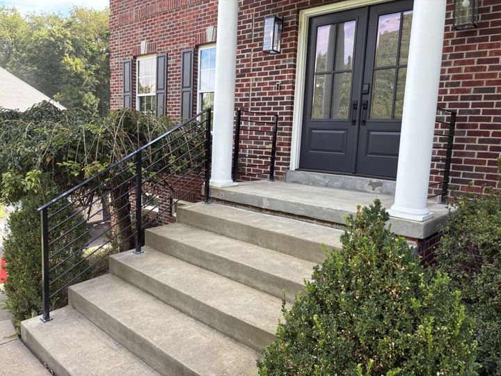 Black aluminum railing with horizontal round pickets beside brick front steps
